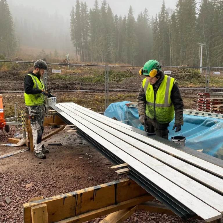 Målare förbehandlar fasadpanel på bygget av Timber Heights i Lindvallen