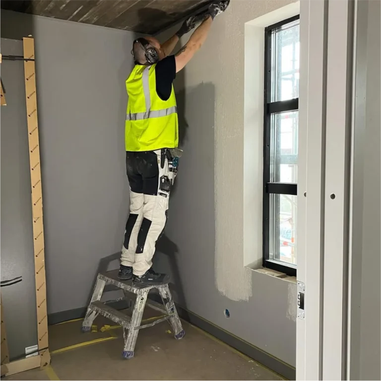Målare spacklar en vägg vid fönstret i Timber Heights