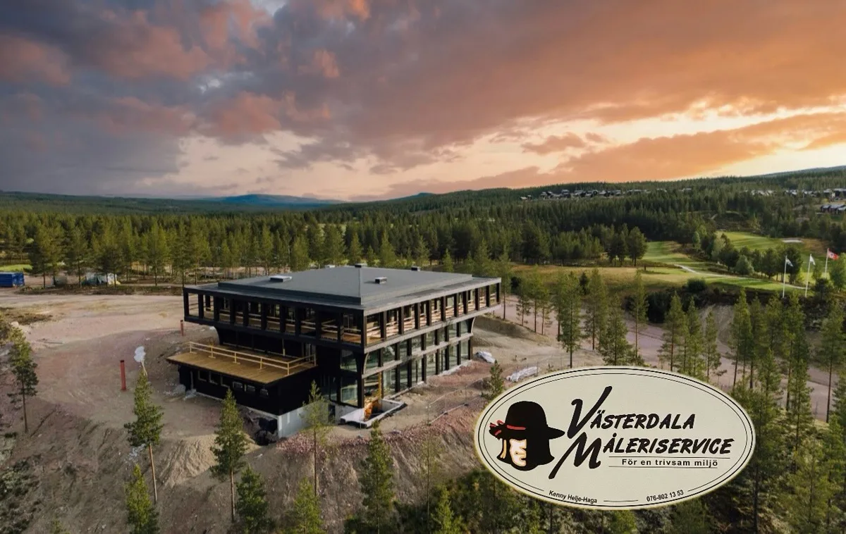 Mörk hotellbyggnad med trädäck och stora fönster bland tallar, golfbana och solnedgång i bakgrunden
